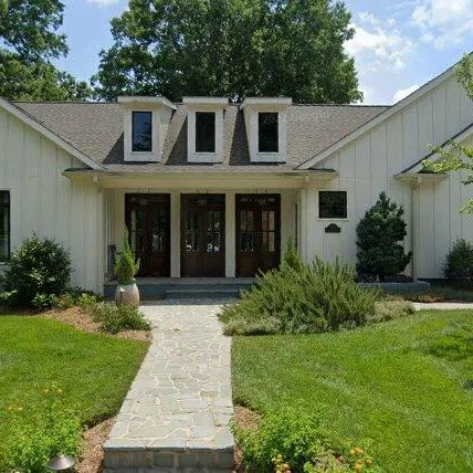 White farmhouse with dormers and landscaping